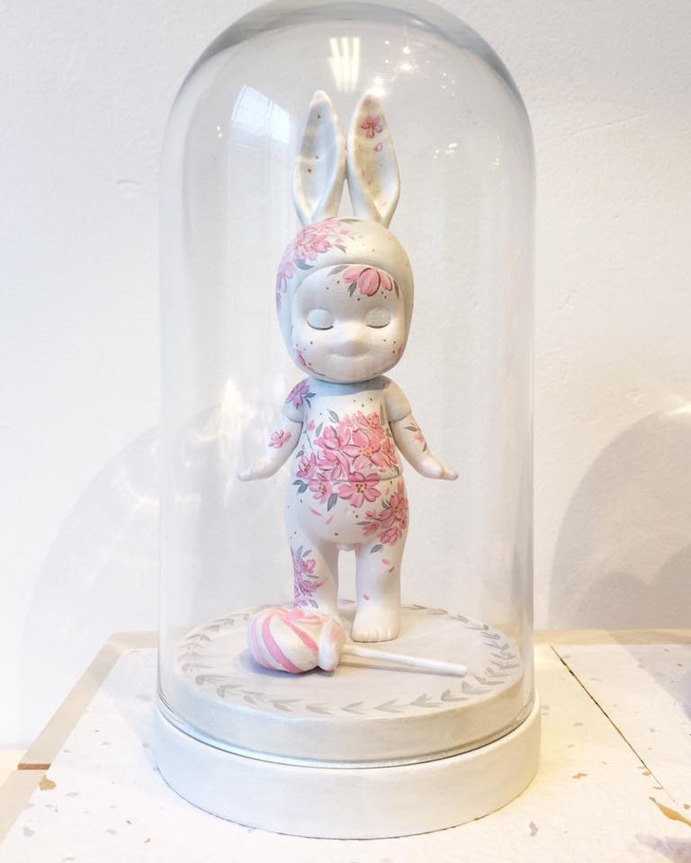 Hand-painted 6" #sonnyangel figure with sakura motif on pearlescent body / lollipop accessory on custom painted wooden base with glass dome at 8". Exclusively available at DesignerCon